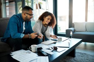 House, couple and documents for budget, laptop and planning for invoice, savings and home loan. Apartment, man and woman on sofa, pc and paperwork for last will and testament with mortgage payment
